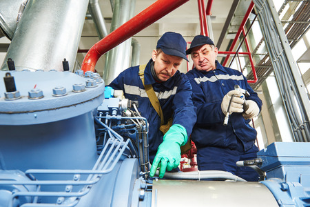 service engineer worker at industrial compressor refrigeration station repairing and adjusting equipment at manufacturing factoryの写真素材