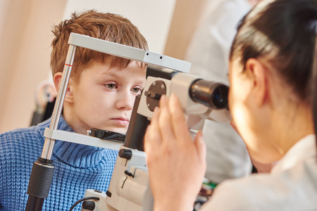 Child optometry. female optometrist optician doctor examines eyesight of little boy patient in eye ophthalmological clinicの写真素材