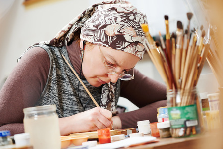 iconography. painter woman paints a new icon with brush at workshopの写真素材