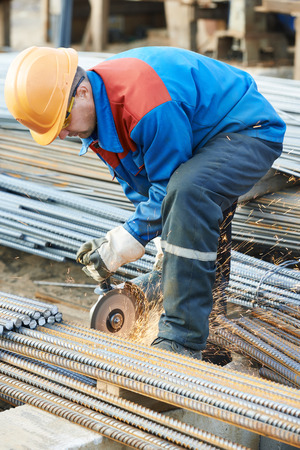 Construction builder worker with grinder machine cutting metal reinforcement rebar rods at building siteの写真素材