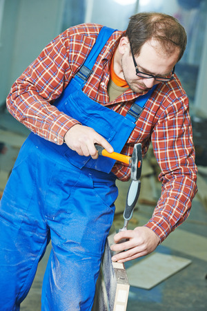 carpenter installer works with hammer and chisel at interior wood door installationの写真素材