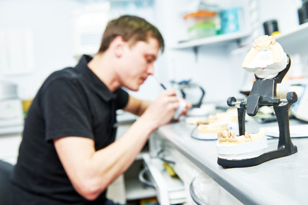 Dental technician working with tooth dentures at prosthesis laboratoryの写真素材