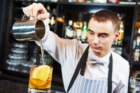 young barman worker at bartender desk in restaurant bar preparing coctailの写真素材