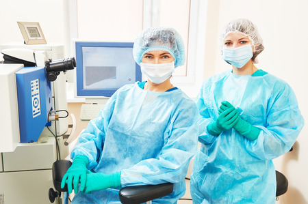 Female surgeon and assistant nurse portraits in uniform in eye vision surgery operation room at medical clinicの写真素材