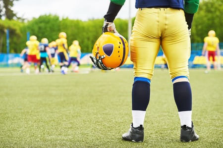 American football player with helmet in hand watching the game