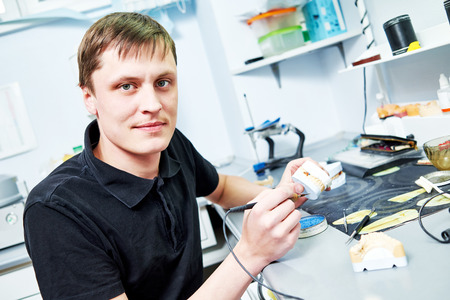 Dental technician working with tooth dentures at prosthesis laboratory