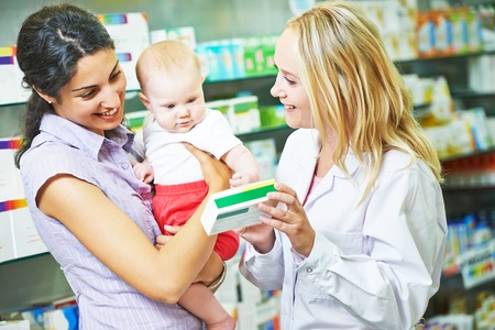 pharmacist chemist woman giving vitamins to mother with child in pharmacy drugstoreの写真素材