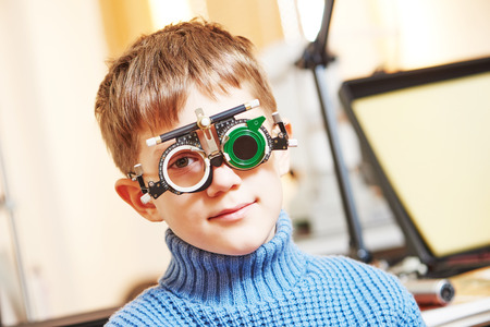 ophthalmology concept. young boy with phoropter during sight testing or eye examinations in clinicの写真素材