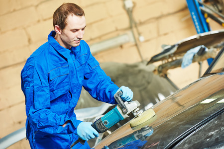 mechanic polishing car body at automobile repair and renew service station shop by power buffer...