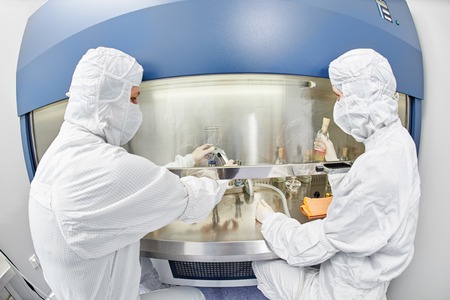 female science researchers in protective uniform and equipment works with dangerous hazard virus...
