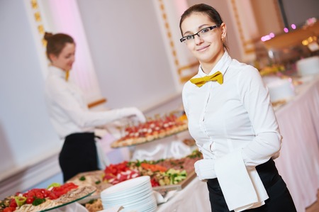 waitress occupation. Young woman with food on dishes servicing in restaurant during catering the eventの写真素材