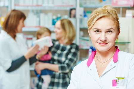 pharmacist woman portrait in front of pharmacy worker demonstrating cream gel to child girl with mother in drugstore. family healthの写真素材