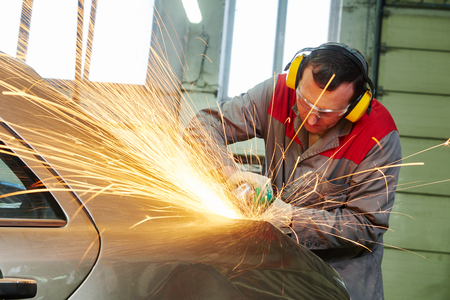 collision repairs service. auto repair mechanic grinding car body by grinderの写真素材