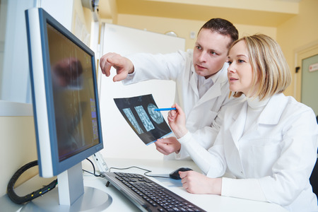 Computed tomography or MRI scanner test. Team of radiologist woman and man examining x-ray image on...