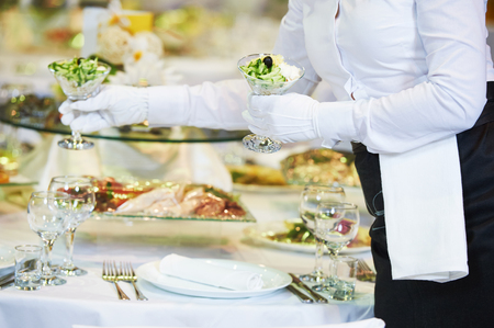 Restaurant catering services. waitress serving banquet table with foodの写真素材