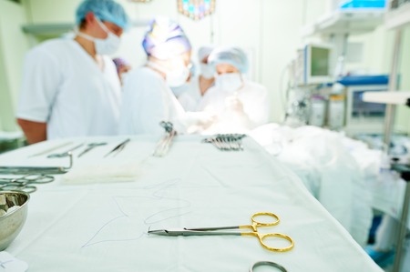 surgery. Surgical instruments in front of surgeon rteam doctors performing abdoinal operation in hospital. Focus on toolの写真素材