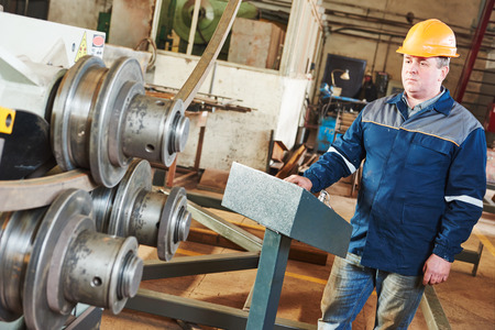 Industrial worker operator of metal pipe bending and punching machine at factory