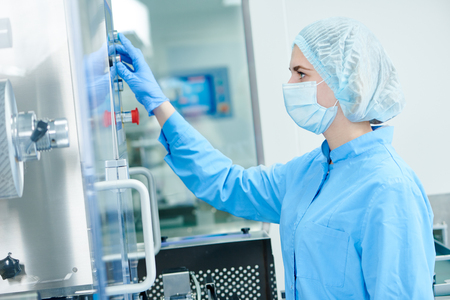 Pharmaceutics tablet production. Pharmaceutical industry worker operates blister and cartoning packaging machine at factoryの写真素材