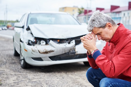 upset driver man in front of wreck automobile after crash car collision accident in city roadの写真素材