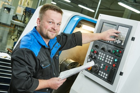 Industrial factory worker or service engineer operating cnc turning lather machine at factory in...
