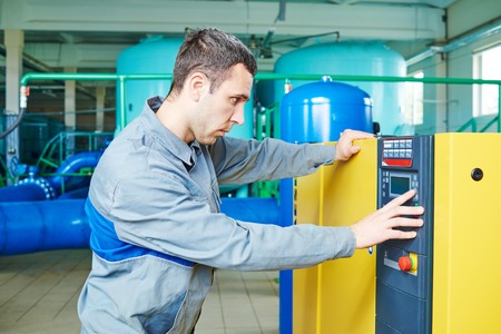 Worker serviceman operating industrial water purification filtration equipment in boiler room or treatment plantの写真素材