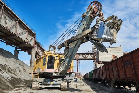 mining industry. Heavy excavator loading gravel into railway cargo train for rail freightage