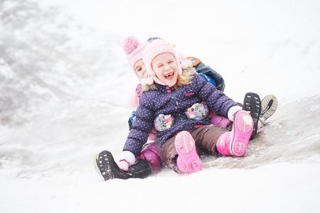 Children girls having fun in winter riding ice slideの写真素材