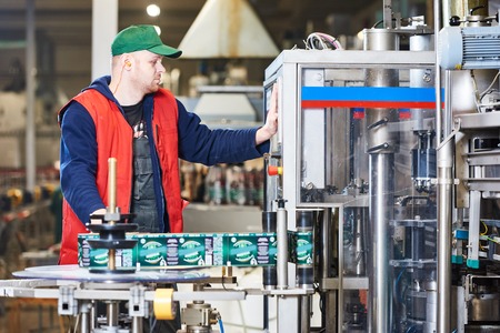 worker operating conveyor or labeling machine at factory