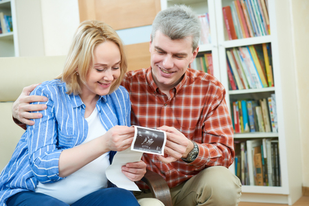Happy couple at home discussing ultrasound scan imageの写真素材