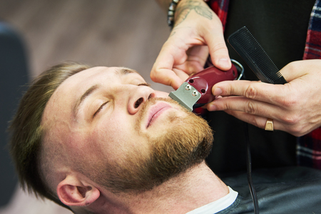 Beard care. man while trimming his facial hair cut at the barbershopの写真素材