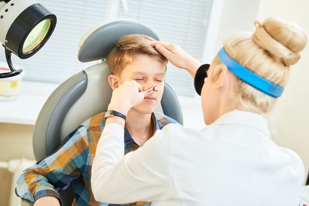 female doctor of ENT ear nose throat at work examining girl noseの写真素材