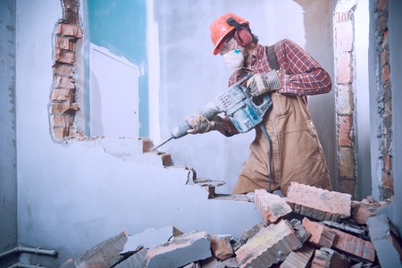 worker with demolition hammer breaking interior wallの写真素材