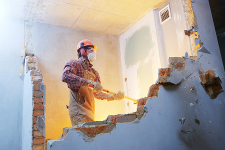 worker with sledgehammer at indoor wall destroyingの写真素材