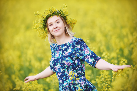 Spring. woman with flower garland at yellow rape seed meadowの写真素材
