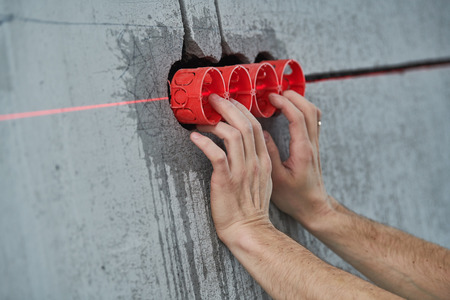 Elecrician work. Installing wall electric outlet with laser level