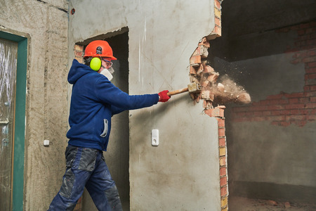 demolition work and rearrangement. worker with sledgehammer destroying wallの写真素材