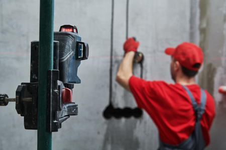 Elecrician work. electric wall outlet installation with laser levelの写真素材