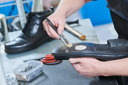 Shoemaker repair shoe. Glueing the sole for male footwear