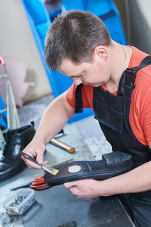 Shoemaker repair shoe. Glueing the sole for male footwearの写真素材