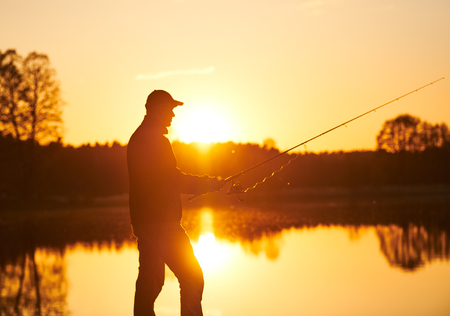 sunset fishing. fisher with spinning rodの写真素材