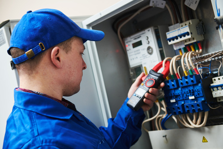 Electrician work concept. Hand with multimeter tester in switchbox