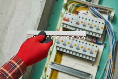 Electrician works with power rail in switchbox. current breaker installationの写真素材