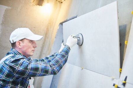 Tiler installing large format tile on wall. home indoors renovationの写真素材