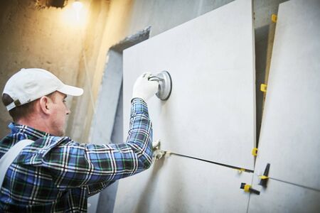 Tiler installing large format tile on wall. home indoors renovationの写真素材