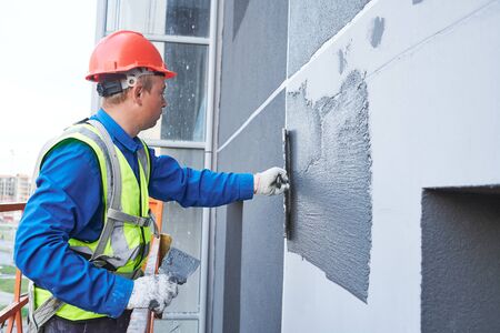 Facade worker plastering external wall of buildingの写真素材
