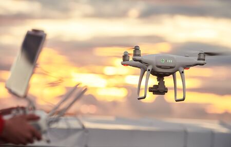 drone quadcopter with digital camera flying at sunset