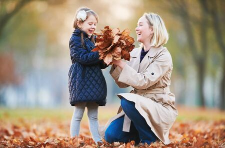 mother playing with little child at autumn parkの写真素材