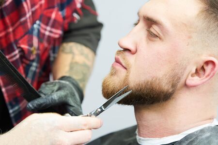 Beard care. man while trimming his facial hair cut at the barbershopの写真素材