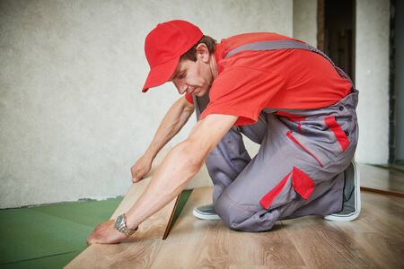 worker laying laminate floor covering at home renovationの写真素材