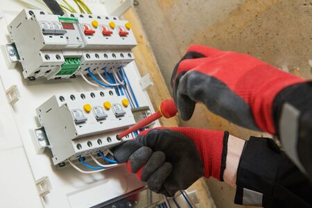 Electrician screwing equipment circuit breaker at electrical fusebox or switch box